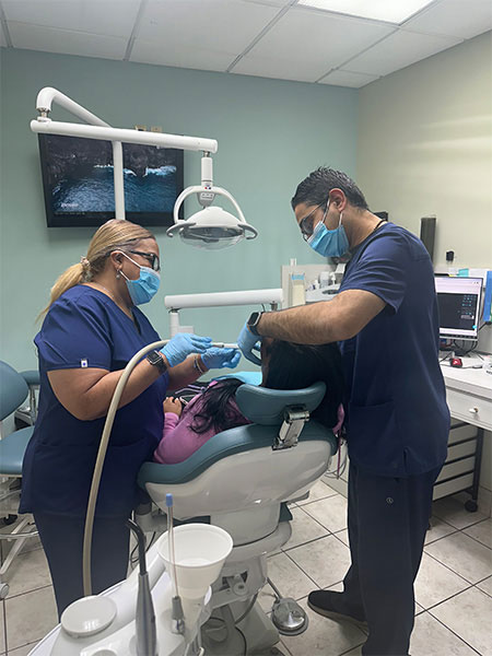 A dental care professional performing a procedure on a patient in an office setting.