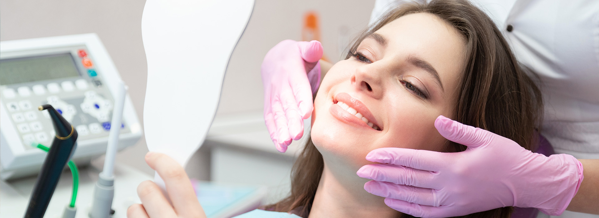 A woman receiving dental care with a dentist s hand holding an instrument near her mouth.