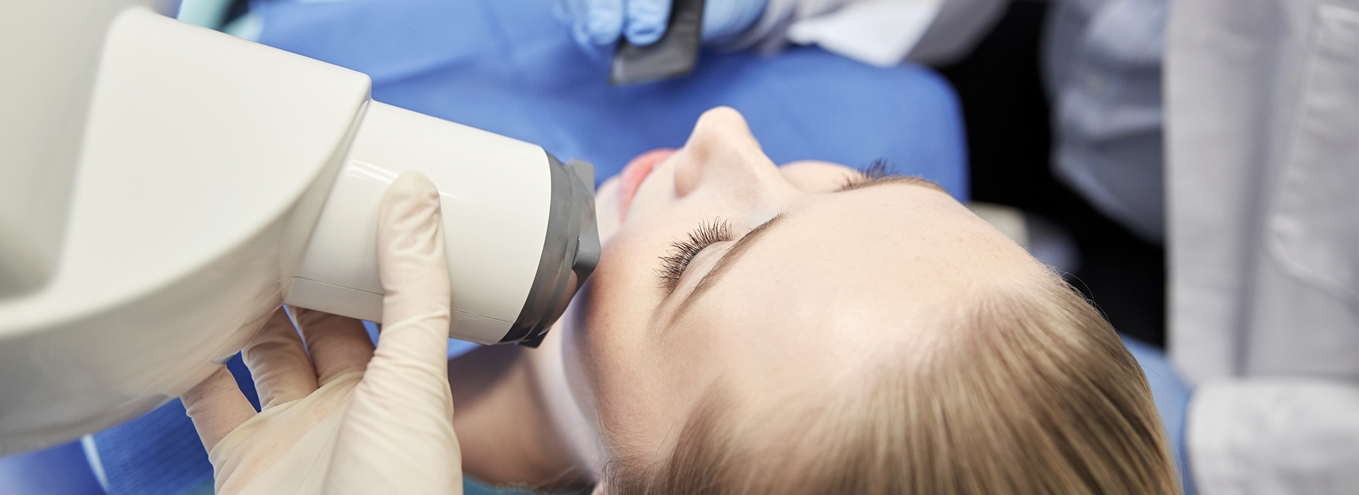 A person receiving a dental implant treatment, with a dentist using a digital scanner to capture the patient s oral details.